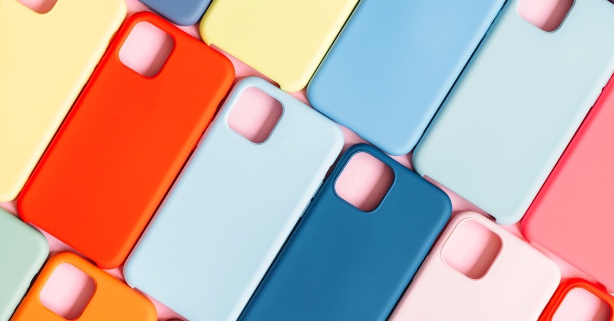 A pattern of multicolored phone cases arranged against a pink background. The cases are shades of blue, orange, and yellow.