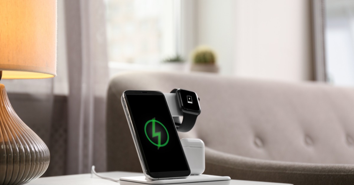 A smartphone standing up on a wireless charging port. There is a smart watch also wrapped around the charging port.