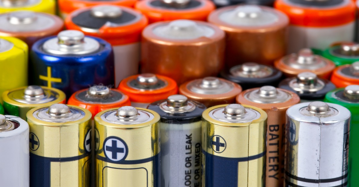 A collection of differently sized, multi-colored batteries all standing next to one another. Smaller batteries are in front.